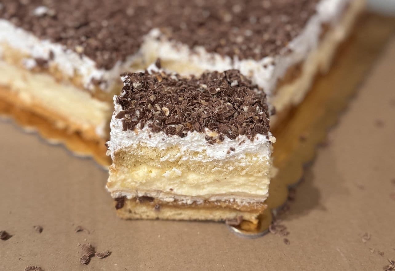 ciasto 3bit - Jasny biszkopt przełożony masą krówkową, herbatnikami, kremem budyniowym oraz kremem śmietankowym. Całość pokryta wiórkami czekoladowymi, oferta cukiernia, tychy, śląsk